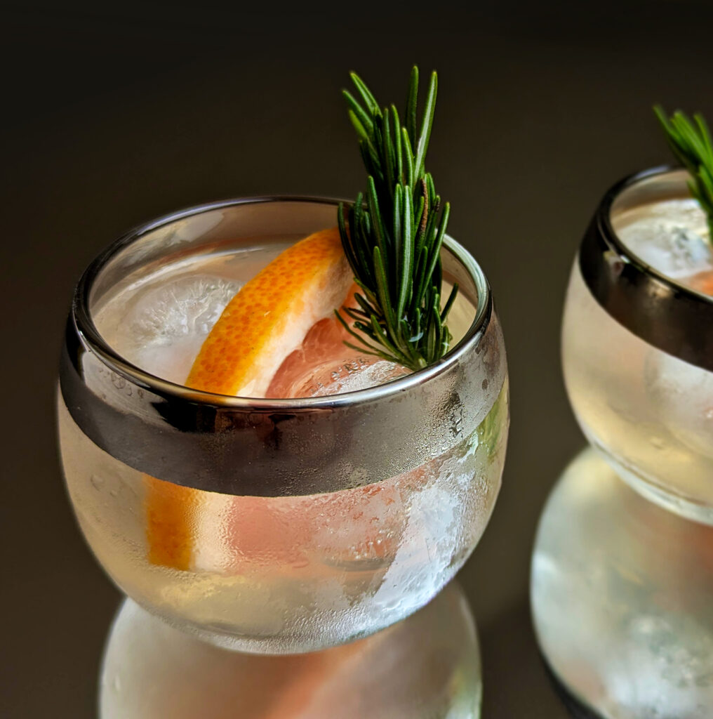 image of a cocktail with gin, grapefuit juice, honey syrup, sparkling water, and a slice of grapefruit and sprig for garnish